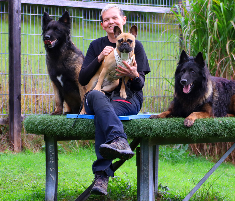 Christa Valentin sitz auf einer Bank mit 3 Hunden